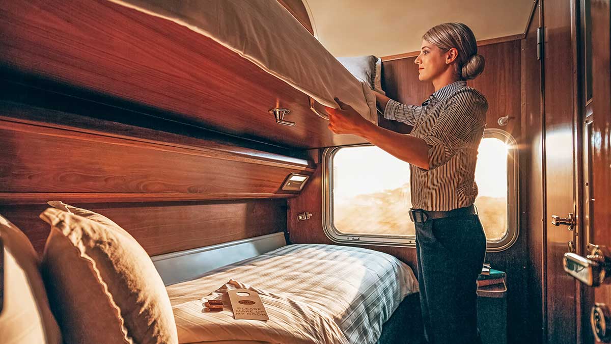 Woman fixing a blanket in a train sleeper cabin