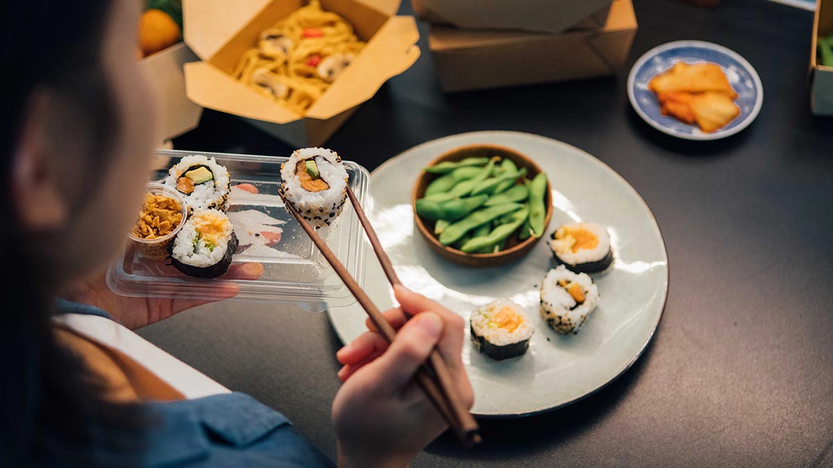 Woman picking up sushi with chopsticks