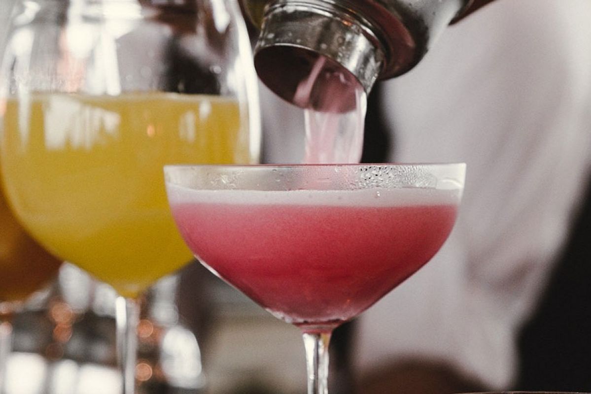 pink mocktail being poured into a glass