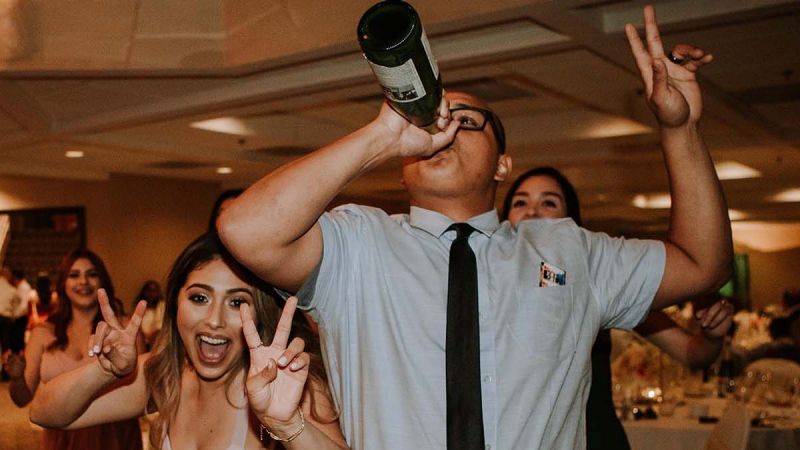 man drinking champagne from the bottle at a party