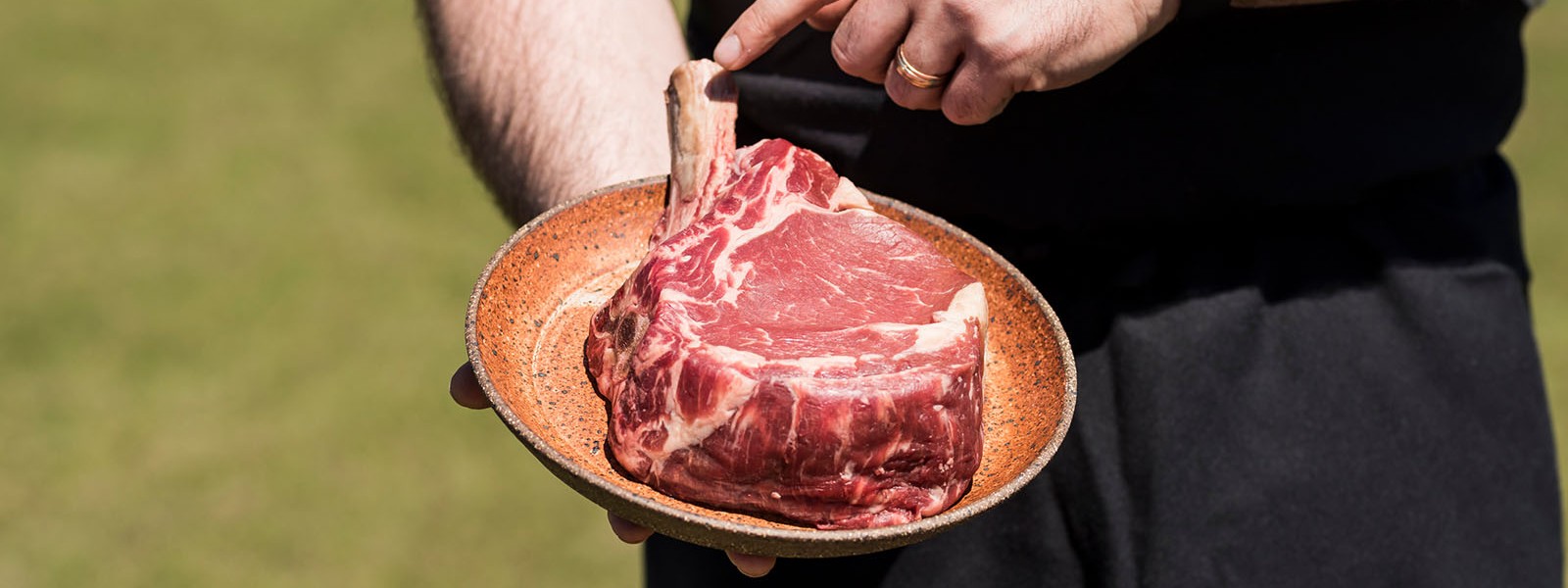 uncooked ribeye steak in shallow orange pocelain bowl