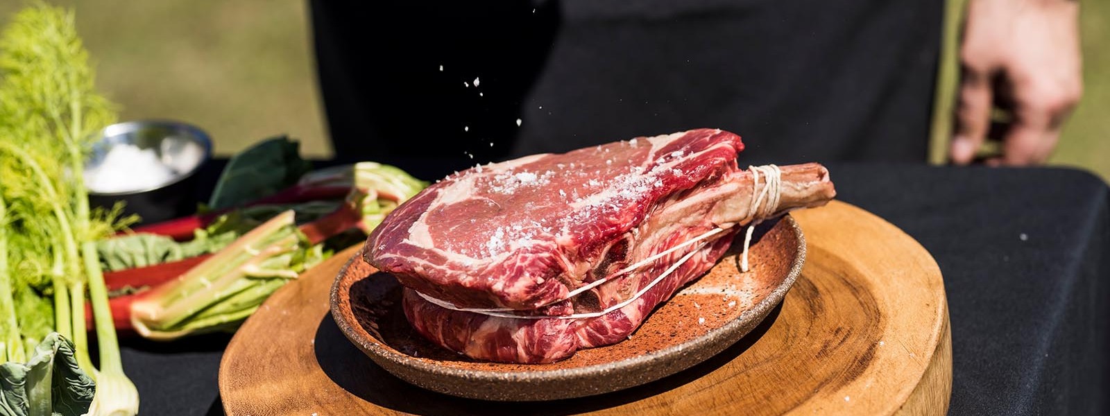 steak being seasoned with salt