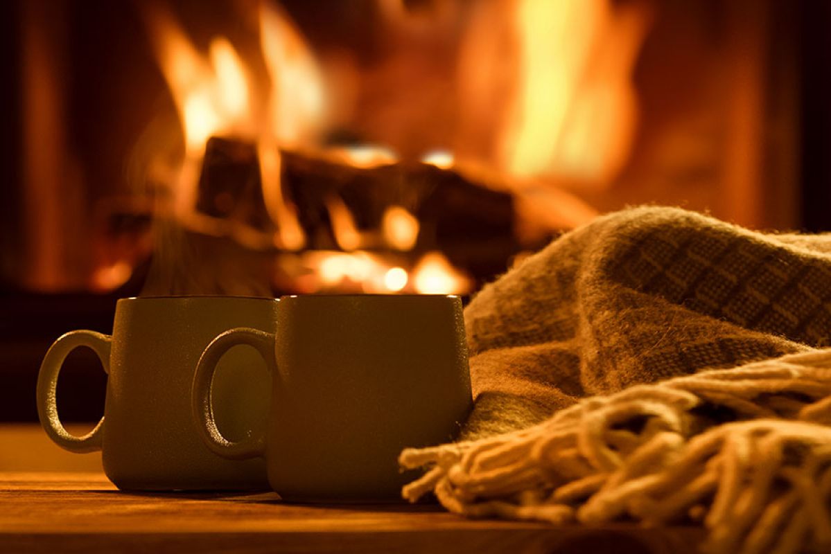 hot drink on table with blanket and fire in the background