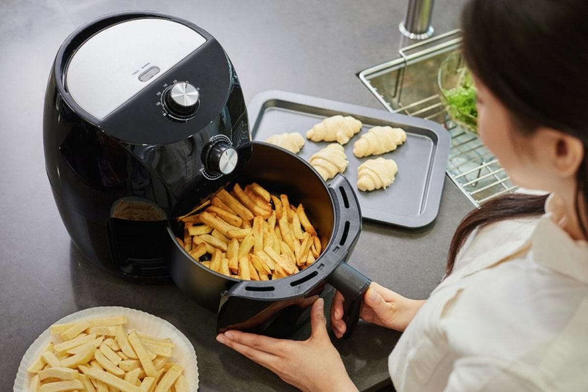 woman using air fryer to cook potato chips