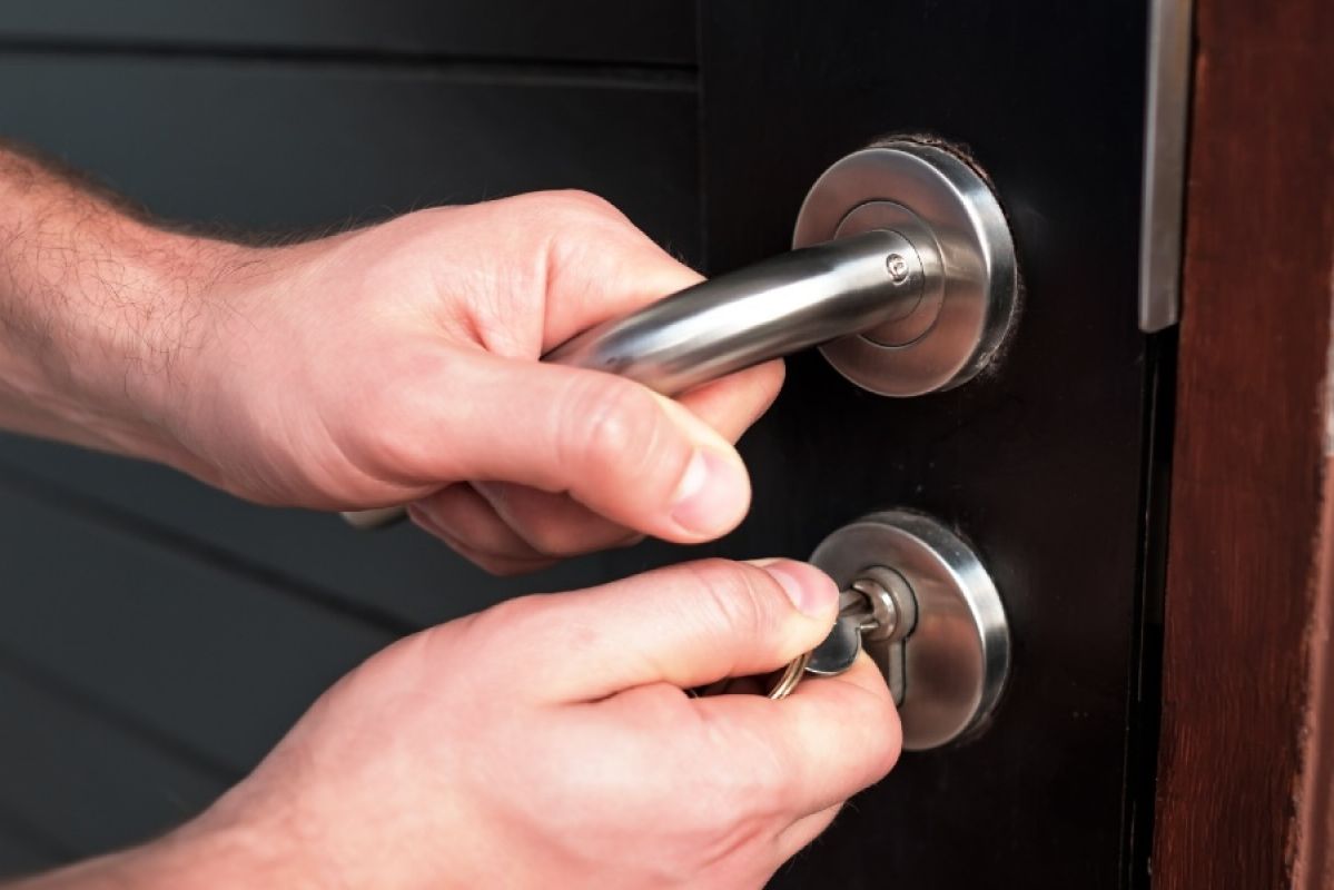 Man opening a door with a lever handle and key lock