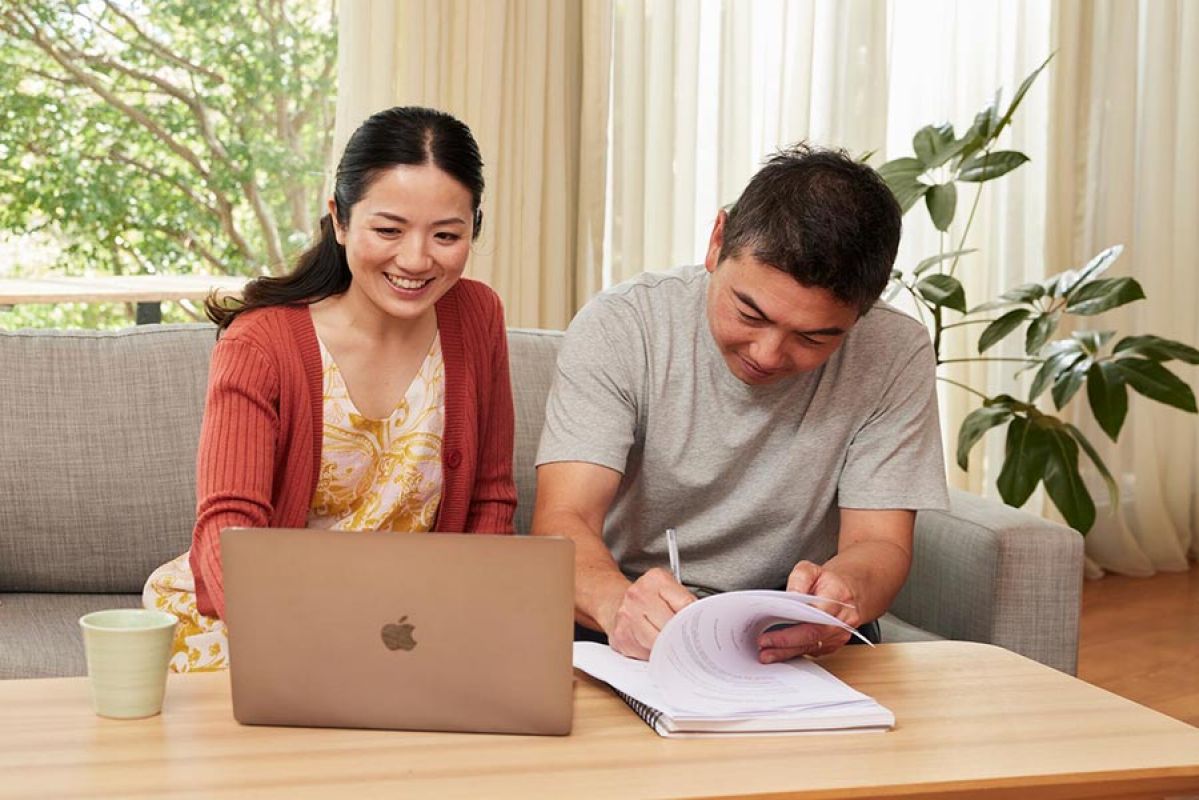 family of three and real estate agent looking at documents while sitting at a kitchen table