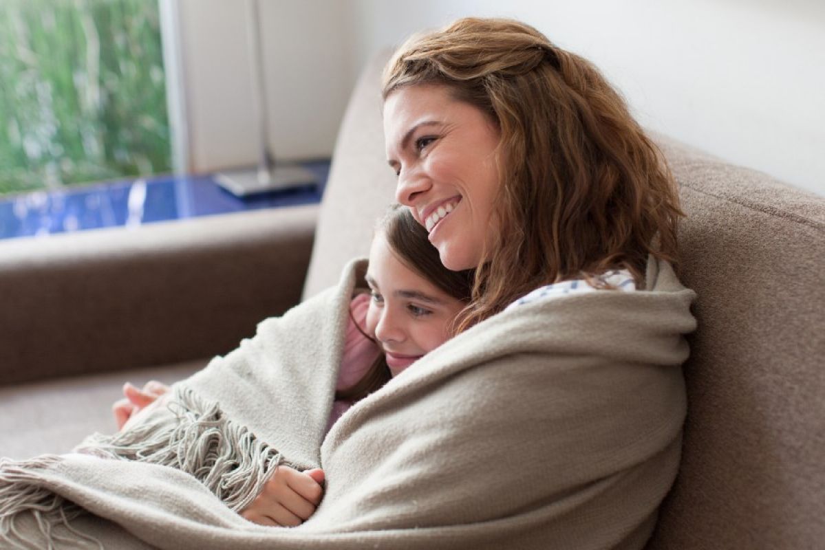 mother and daughter hugging under a blanket