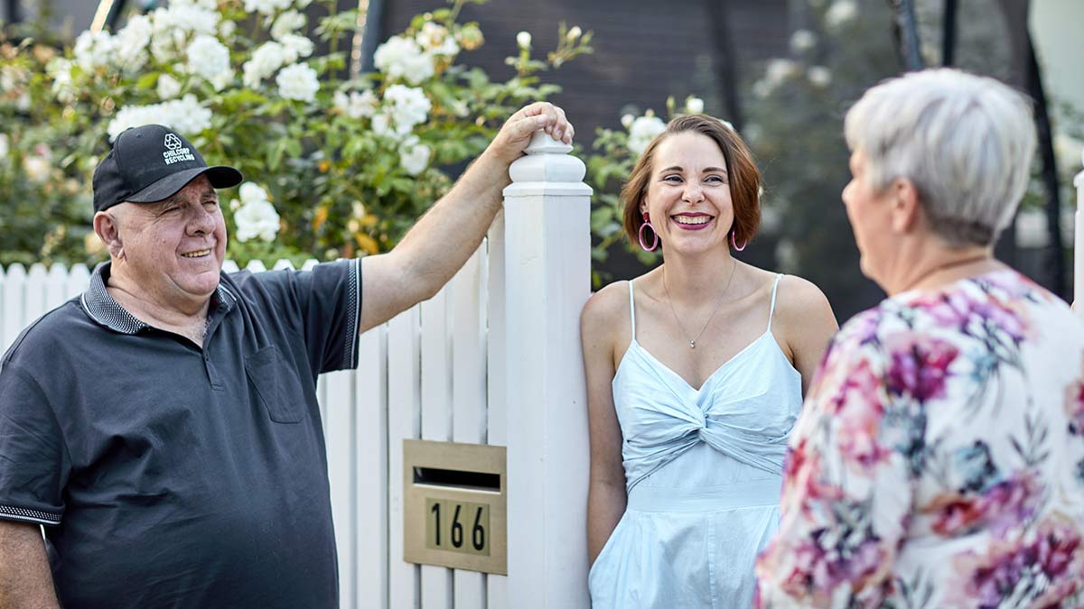 Three people smiling near a fence