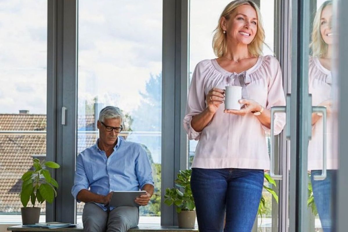 woman standing with coffee cup and man sitting on a table