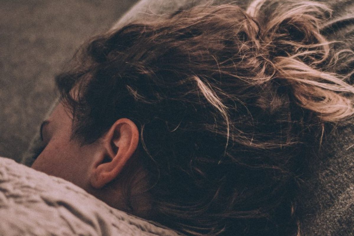 person resting head on pillow under covers