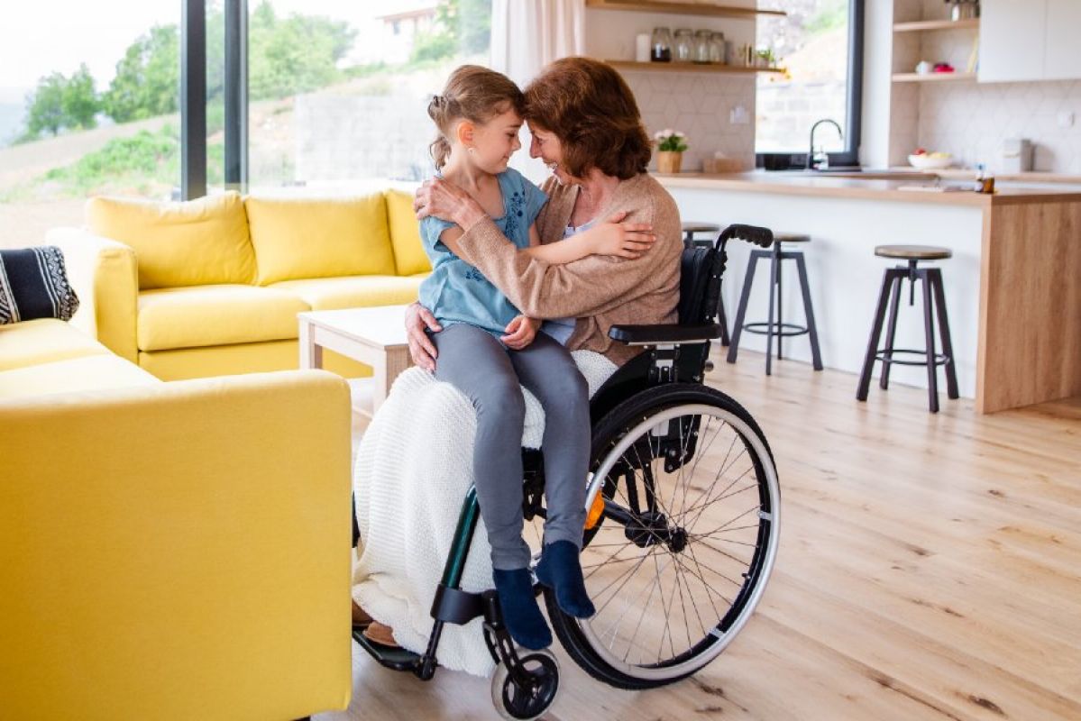 grandmother and granddaughter embracing in grandma's wheelchair in a granny flat