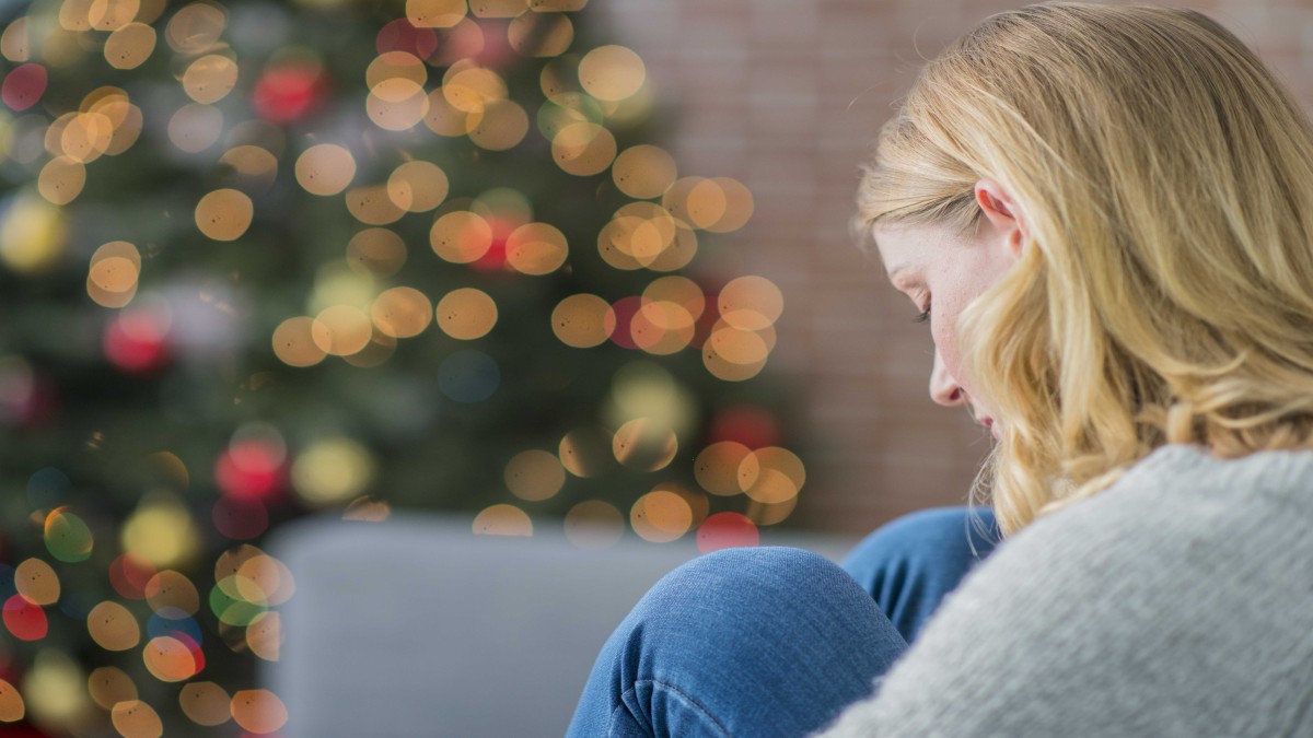 Woman sitting by herself in front of Christmas tree