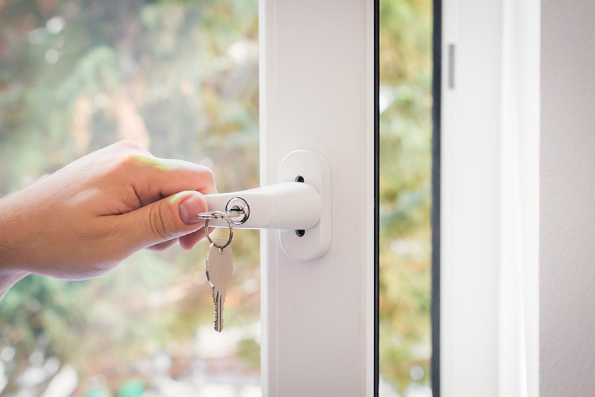 person opening a window with a lever handle and key lock