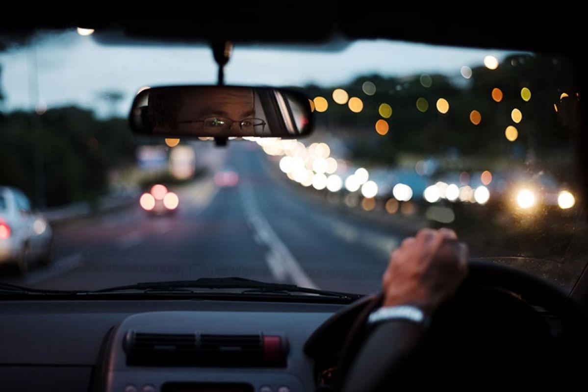 person driving at night into headlights with reflection in the mirror