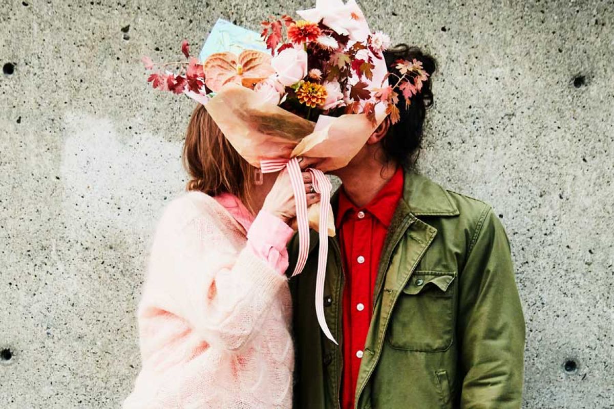 Couple kissing behind flowers