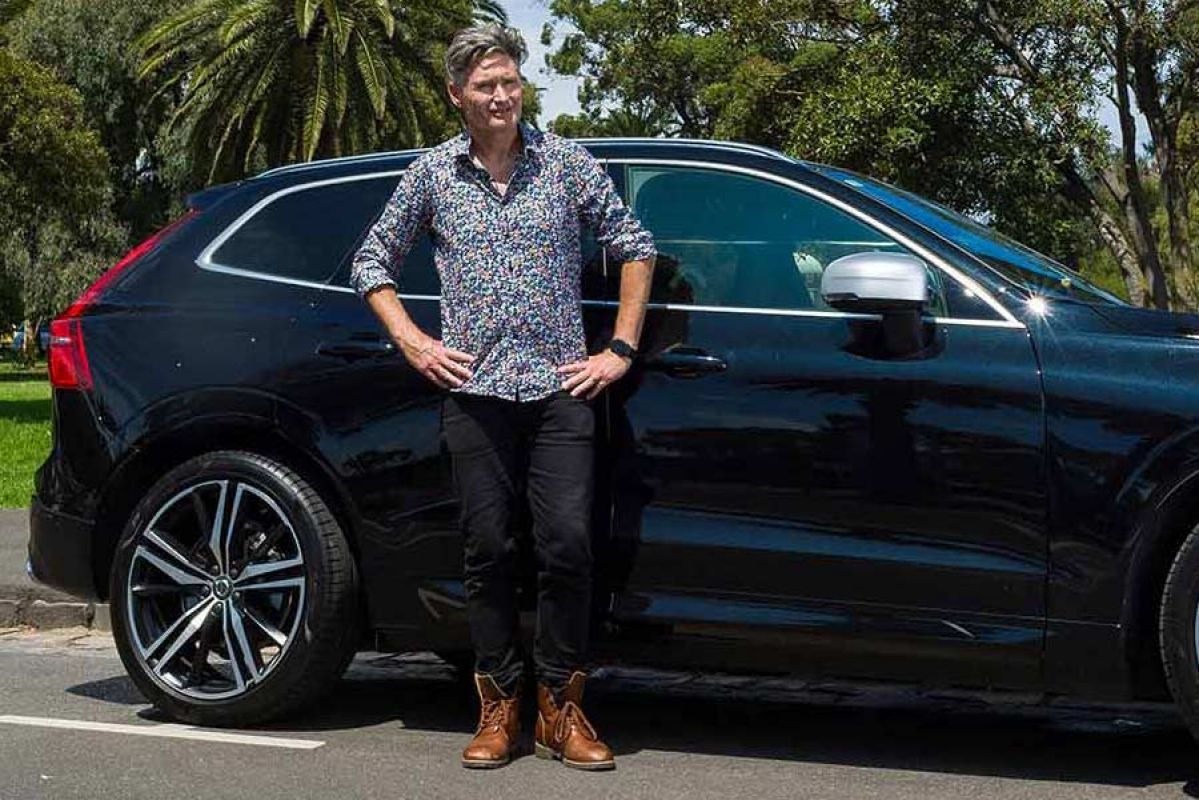 Man stands in front of car with hands on hips.