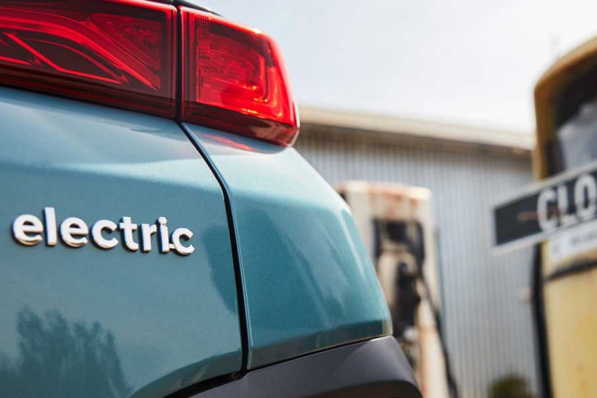 Back of an electric vehicle with an old petrol pump in the background