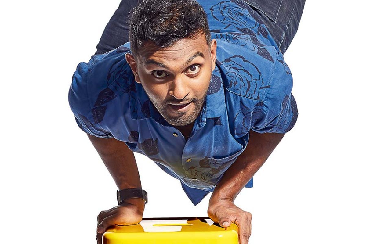 Man balances on yellow stool with hands.