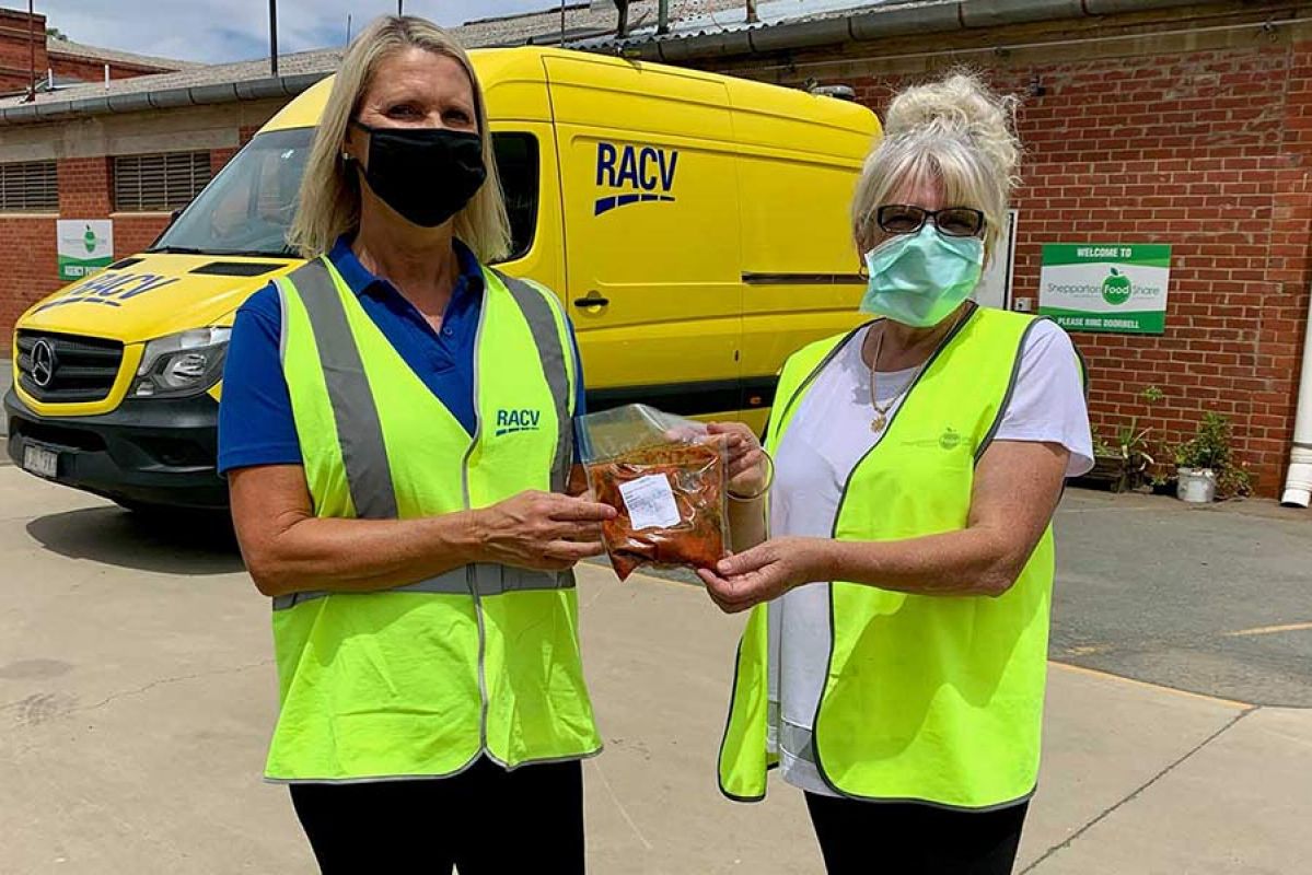 RACV Emergency Goods Assist team members holding a meal in front of an RACV van