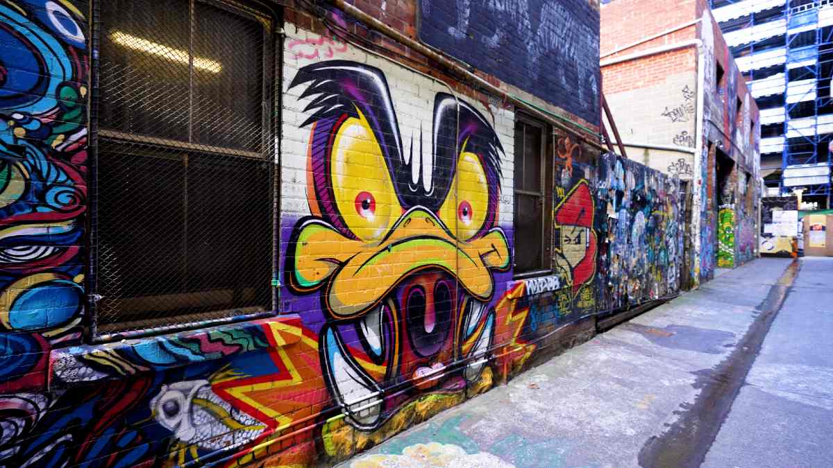 A Melbourne laneway with a mural of a duck-like cartoon monster painted on a wall