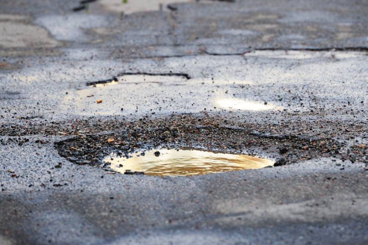 A pothole on the road filled with muddy water