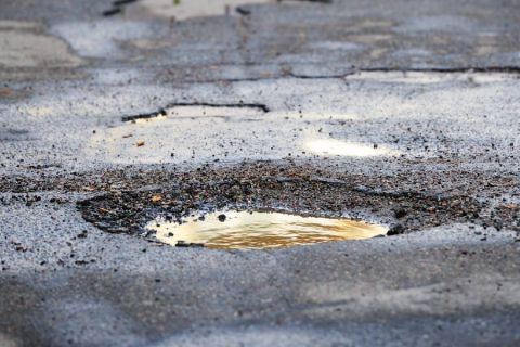 A pothole on the road filled with muddy water