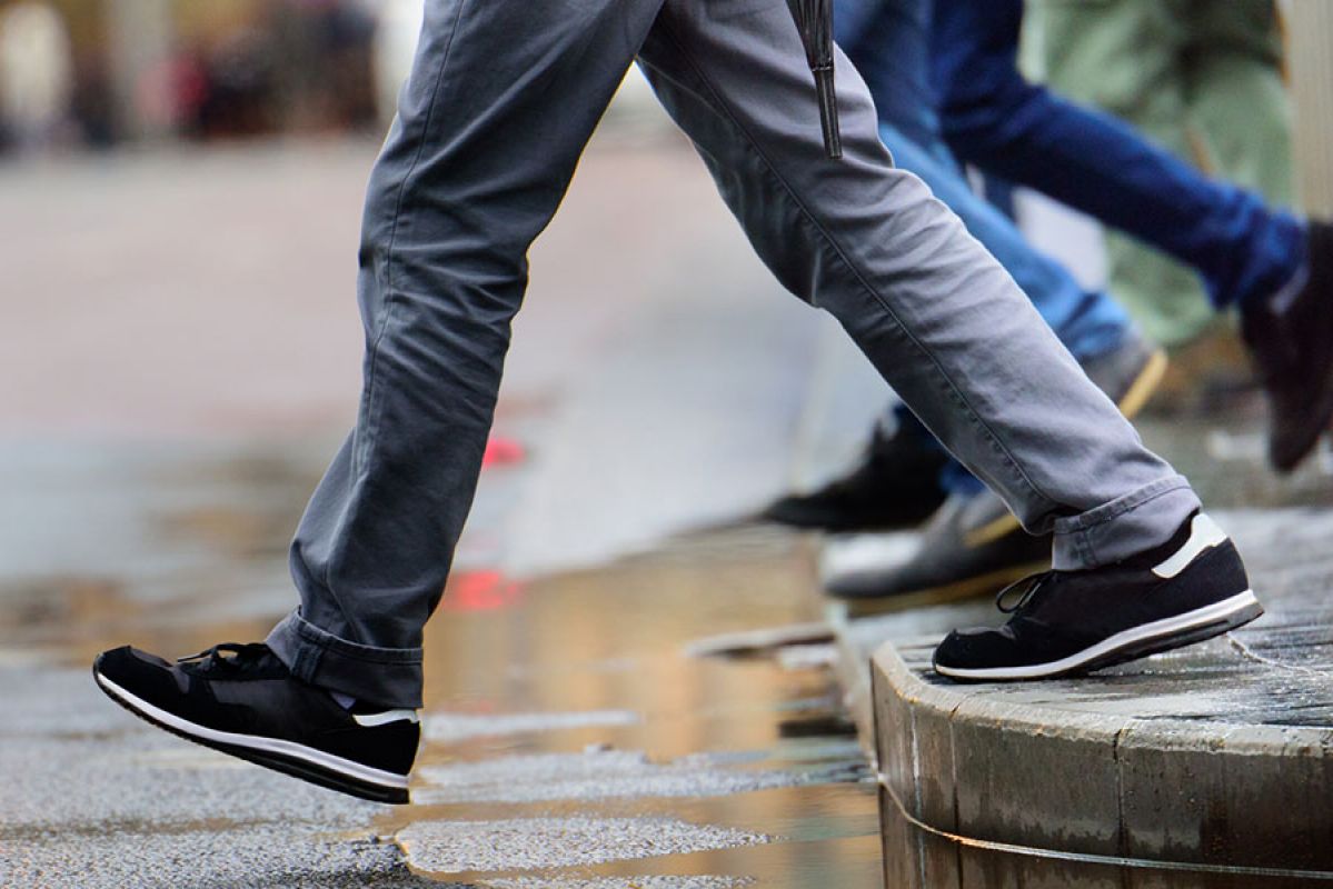 People stepping out onto the road from a kerb on a rainy day