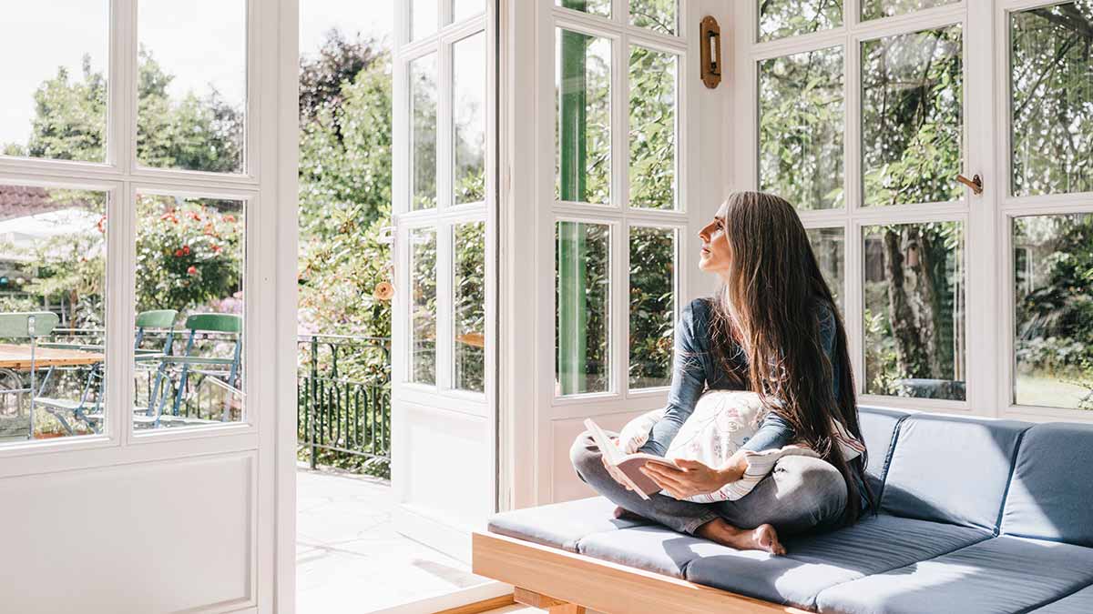 Woman sitting in sun room with door open