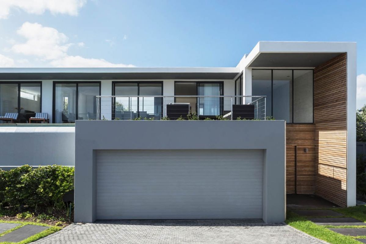 Facade of modern, cube-style double-storey home with double garage, balcony and mixed building materials