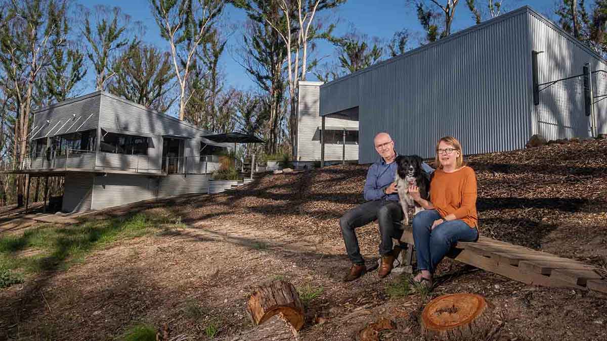 Couple and dog sitting in front of bushfire resilient home