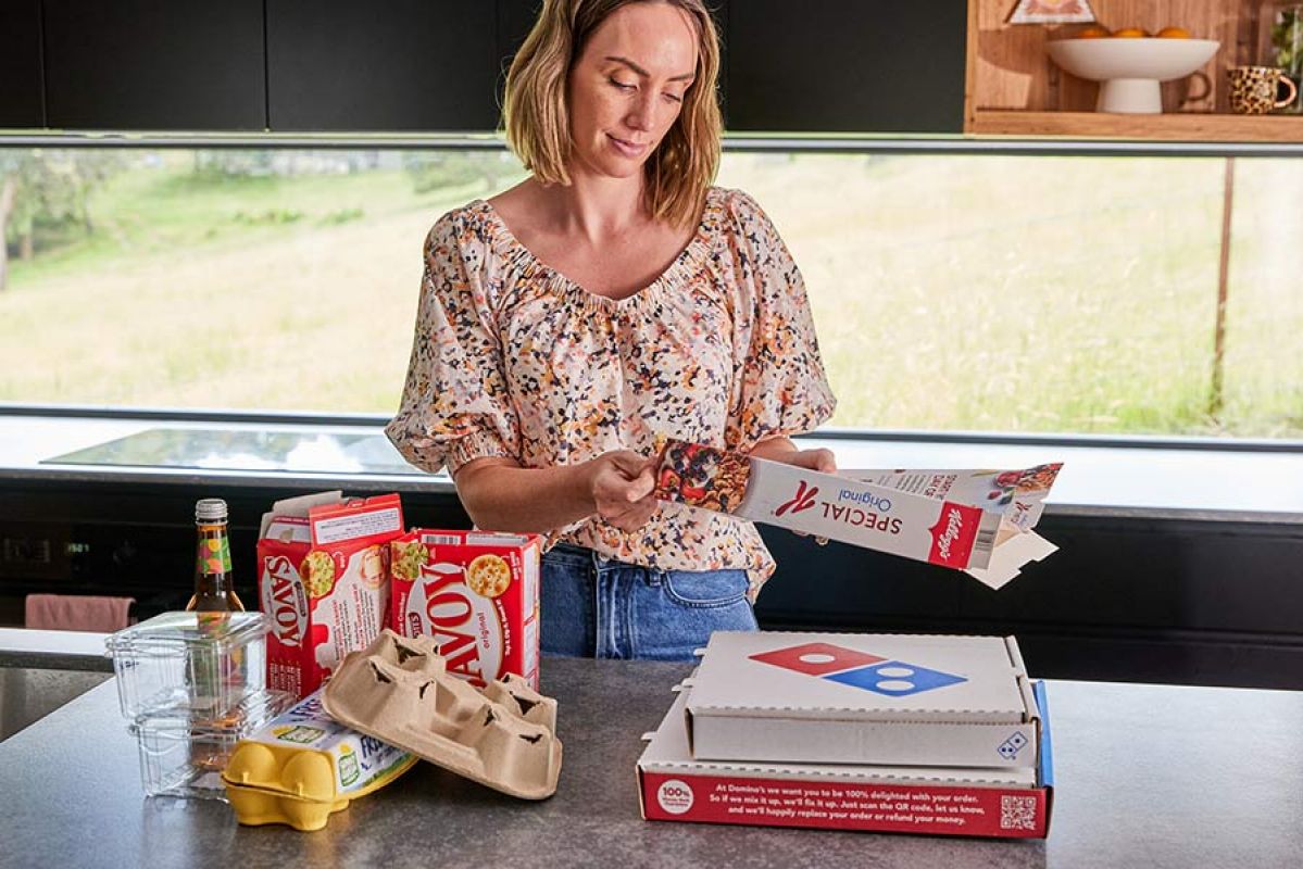 A person folding down cardboard food boxes for recycling