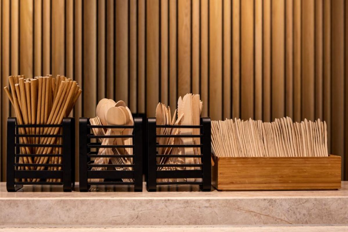 Paper straws, wooden cutlery lined up in a row