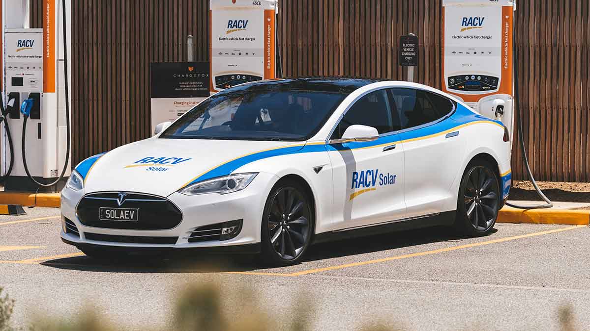 A Tesla at a charging station in RACV Solar branding