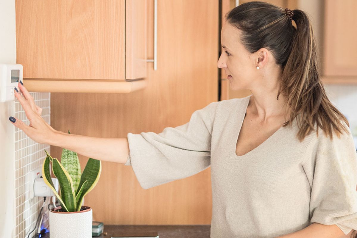 woman changing the temperature on her air conditioning unit