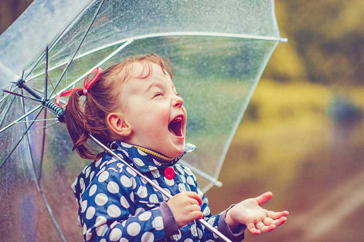 little girl excited by rain under umbrella