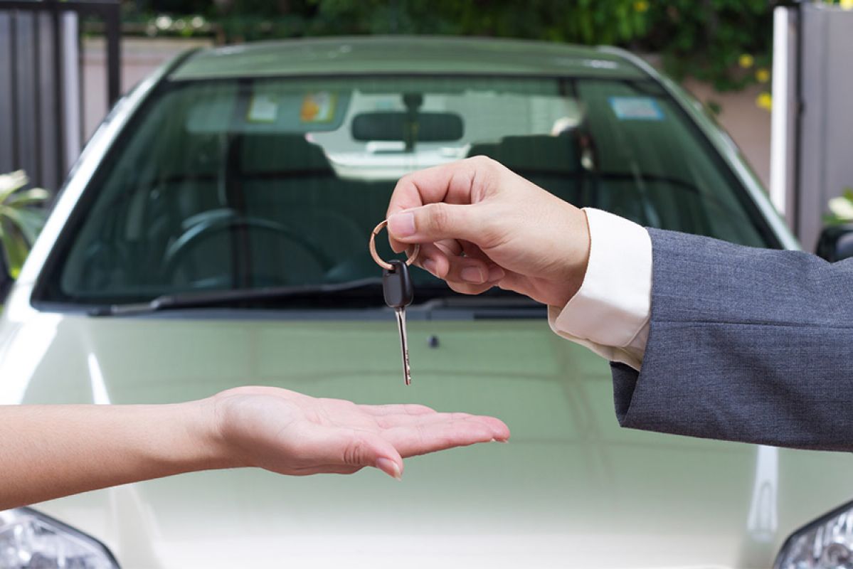 A salesperson handing a car key over to the purchaser