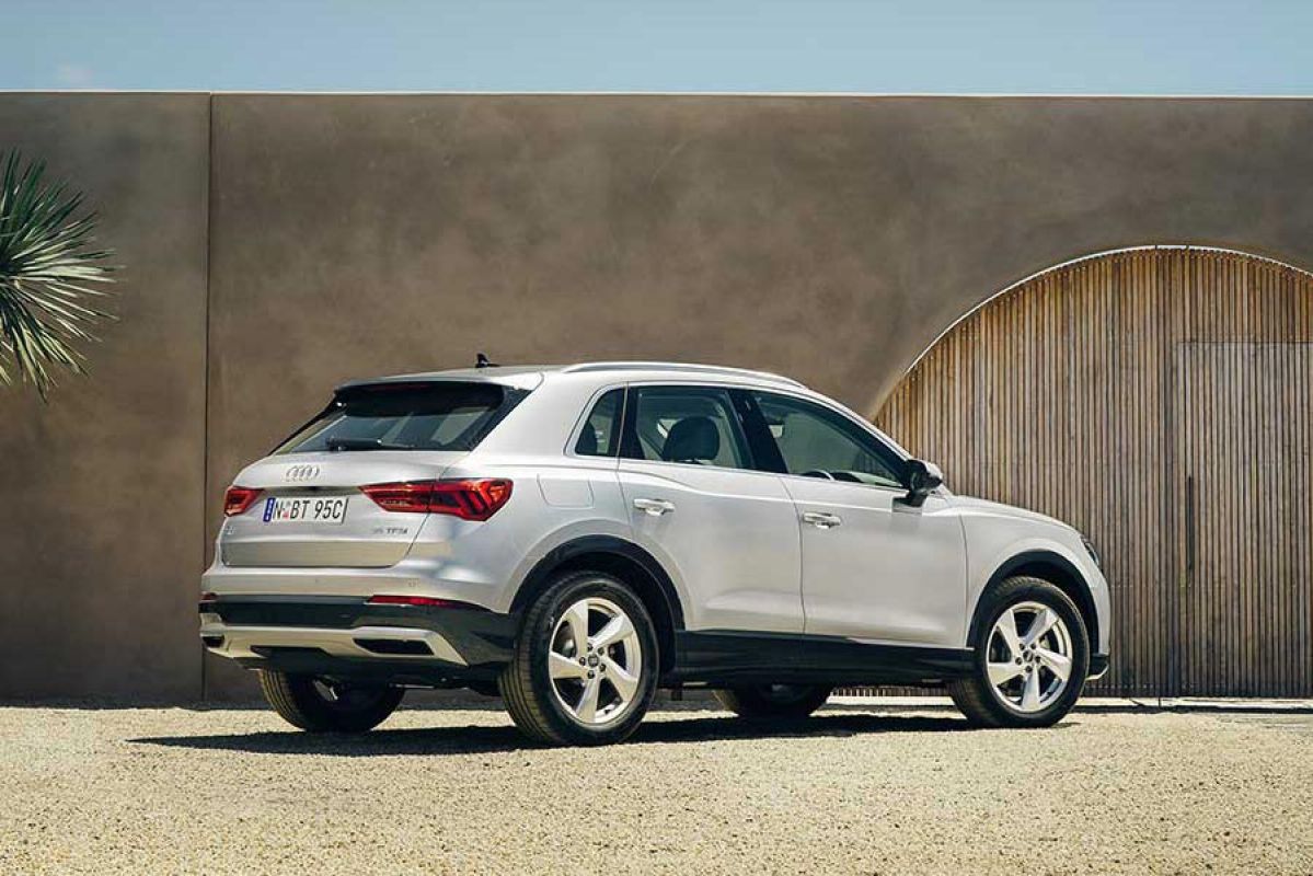 Rear side view of a silver Audi Q3 35 TFSI 2020 car parked in front of a gate