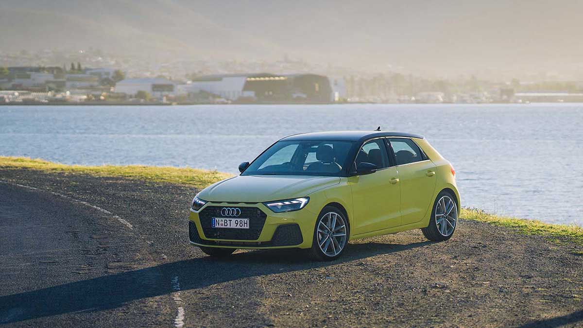 View of lime green Audi A1 parked in front of lake