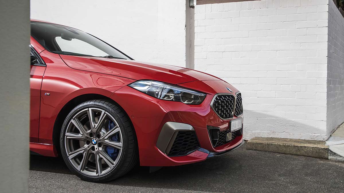 Side view of the front half of a red BMW M235i xDrive Gran Coupe car parked in a laneway