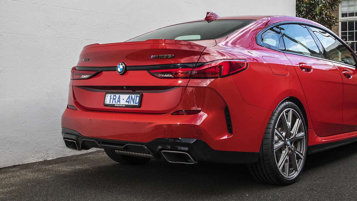 Rear side view of a red BMW M235i xDrive Gran Coupe car parked in a laneway