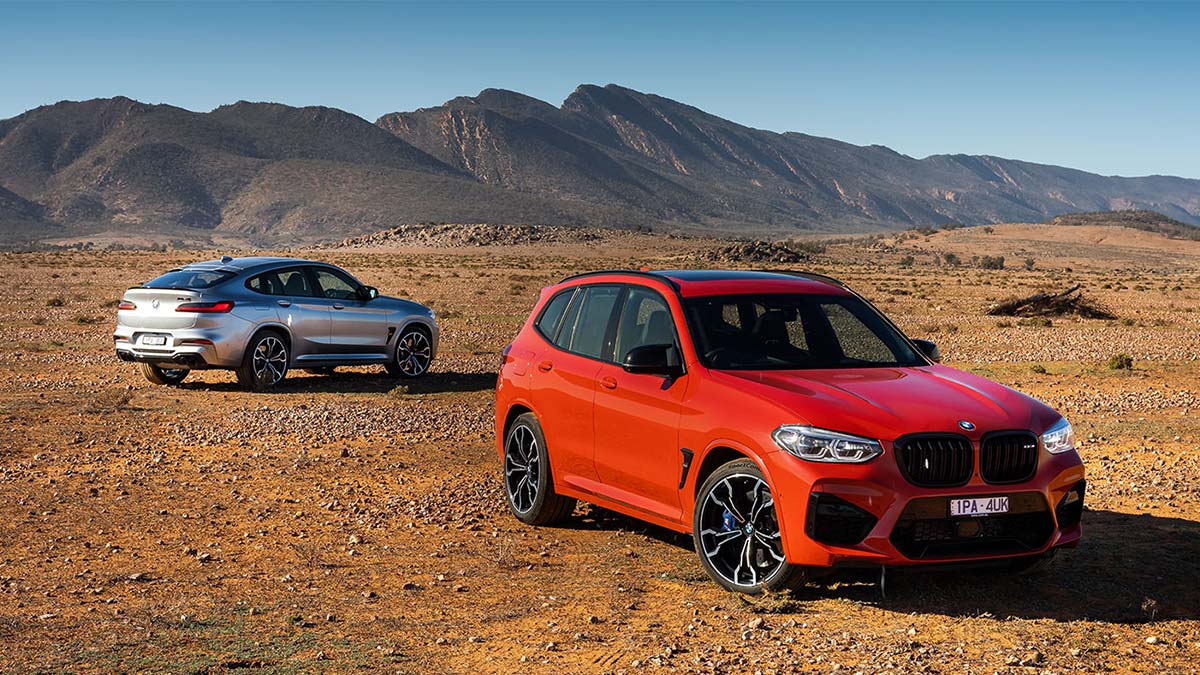 A red and a silver BMW X3 M Competition 2020 car parked in a desert landscape