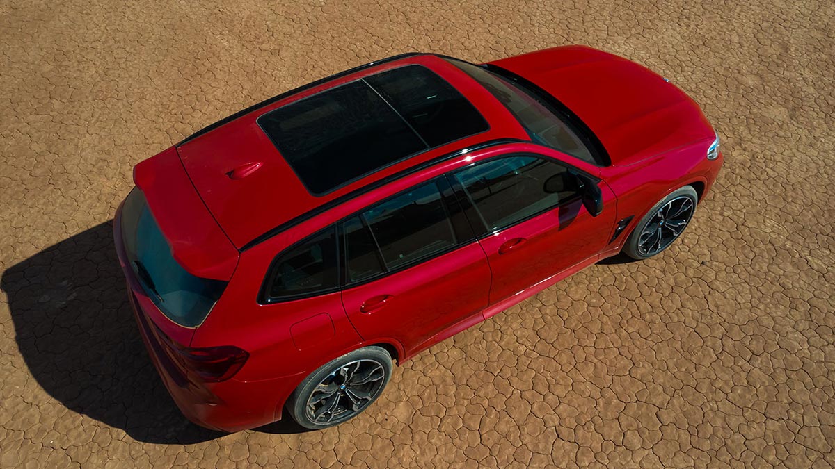 Top view of a red BMW X3 M Competition 2020 car with a sunroof parked on a cracked desert floor