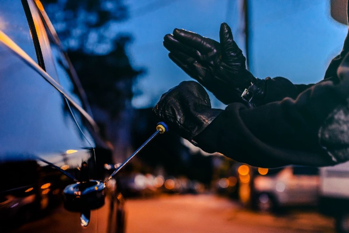 thief breaking into a car with a screwdriver