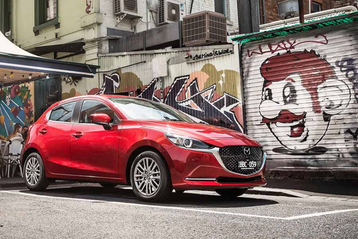 A red Mazda2 in an urban setting surrounded by street art