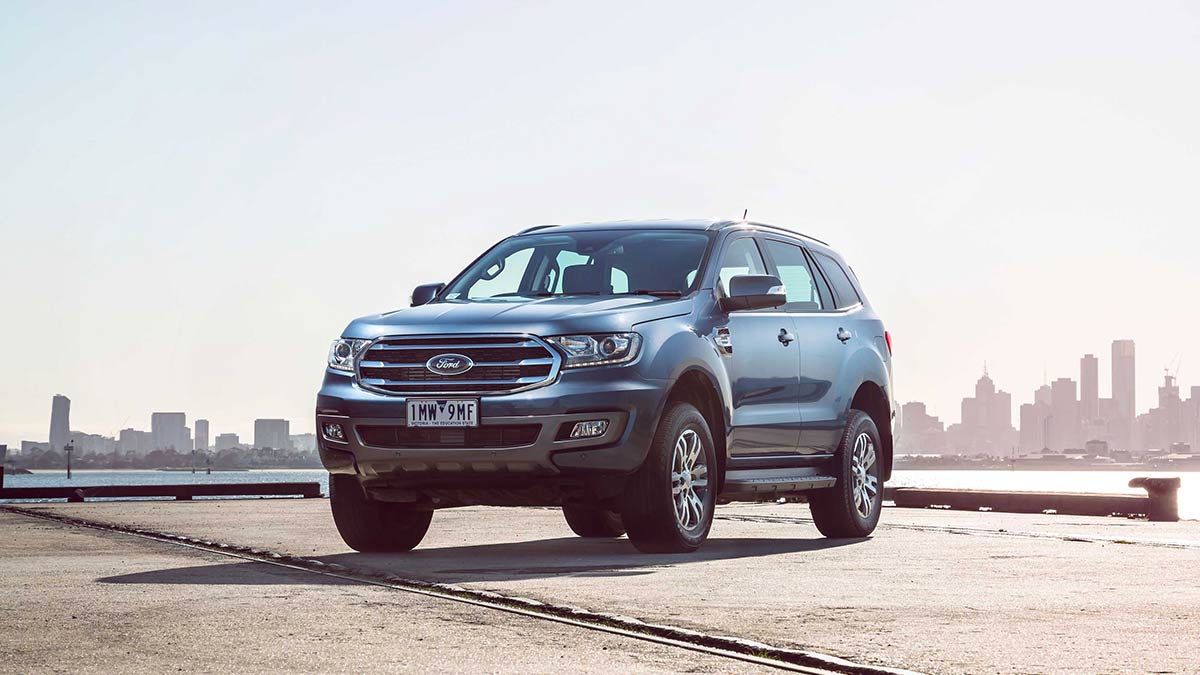 Front side view of a blue Ford Everest parked on concrete with the Melbourne skyline in the background