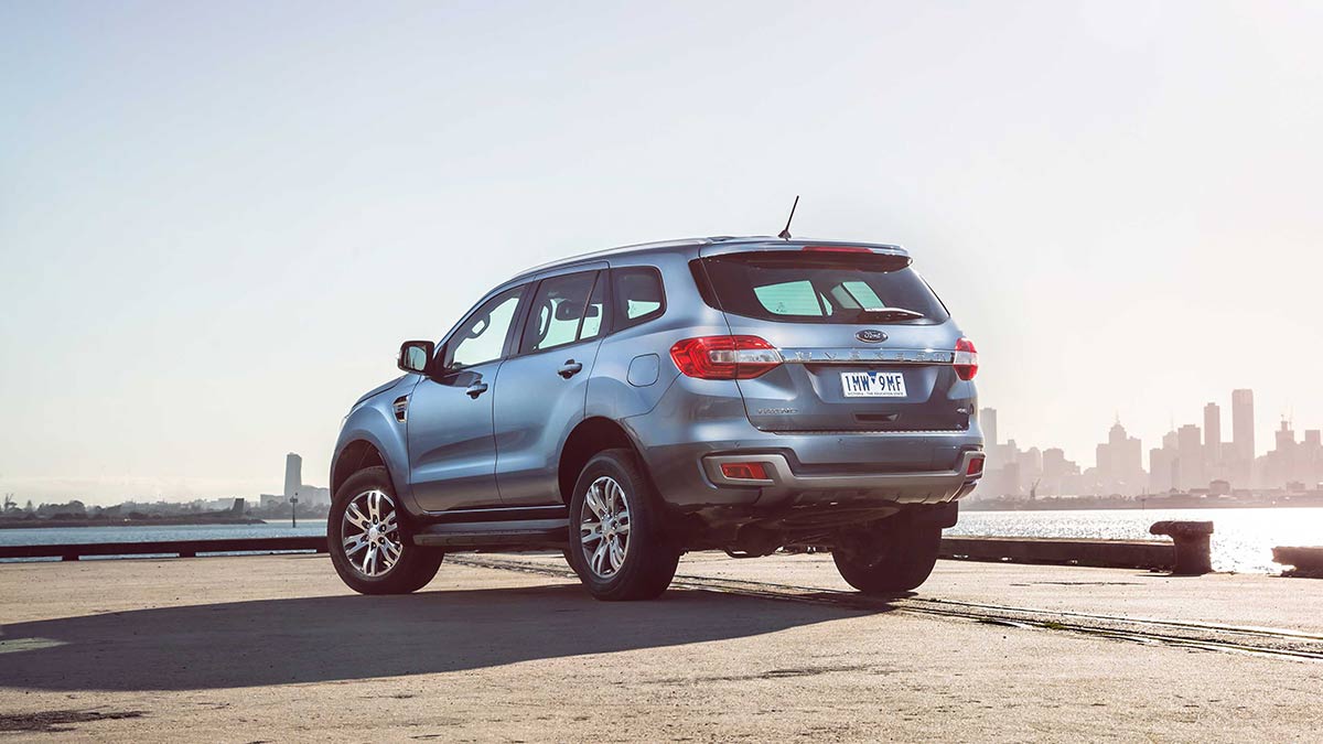 Rear side view of a blue Ford Everest parked on concrete with the Melbourne skyline in the background