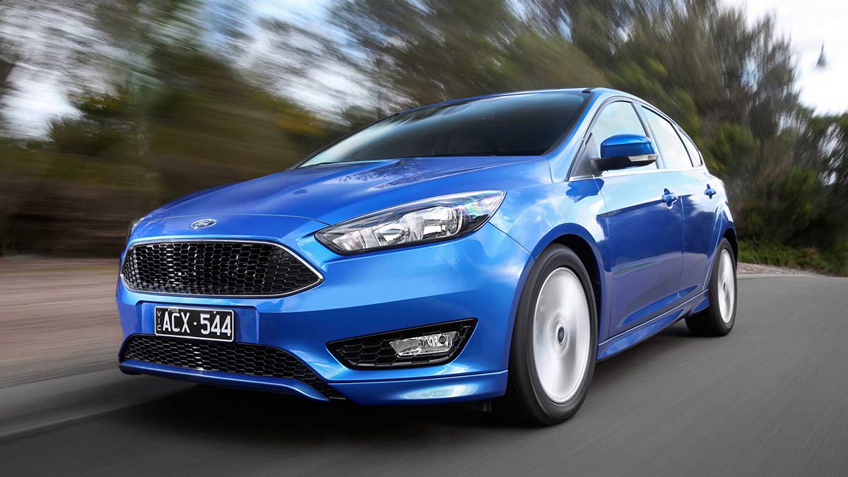 Front side view of a metallic blue Ford Focus LZ car in motion