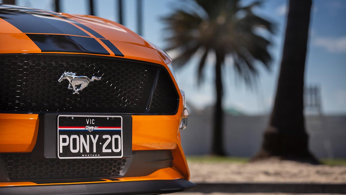 Mustang's emblem on the nose of an orange Ford Mustang