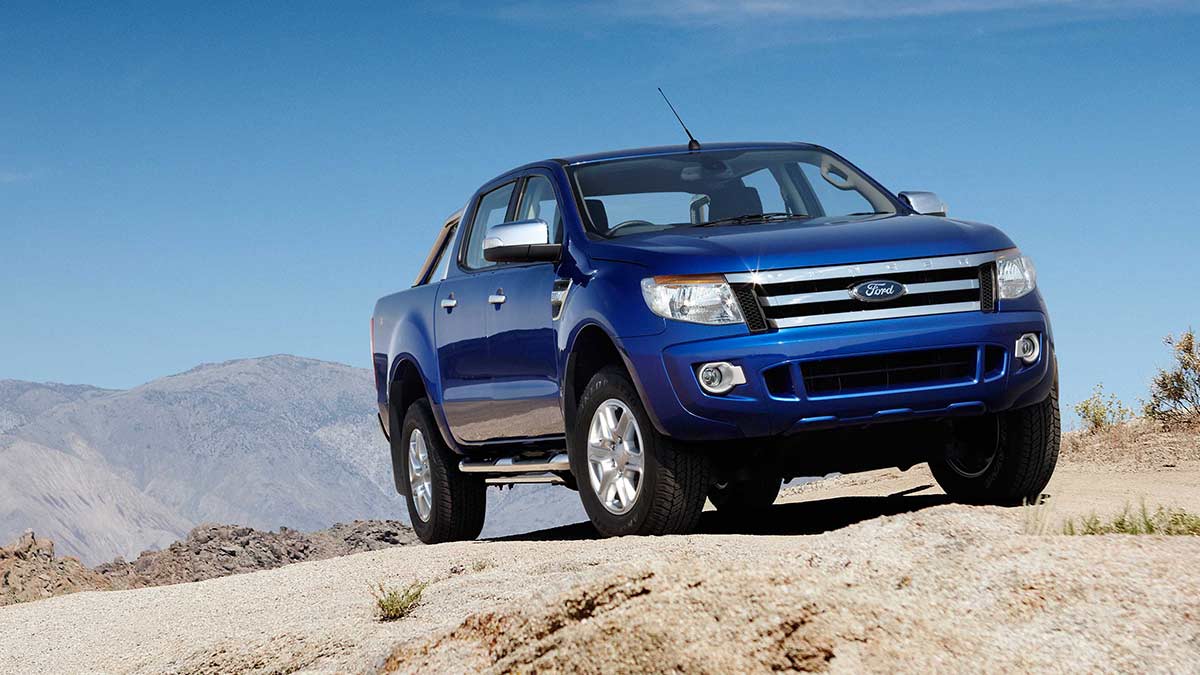 Front side view of a blue Ford Ranger parked in a mountainous landscape