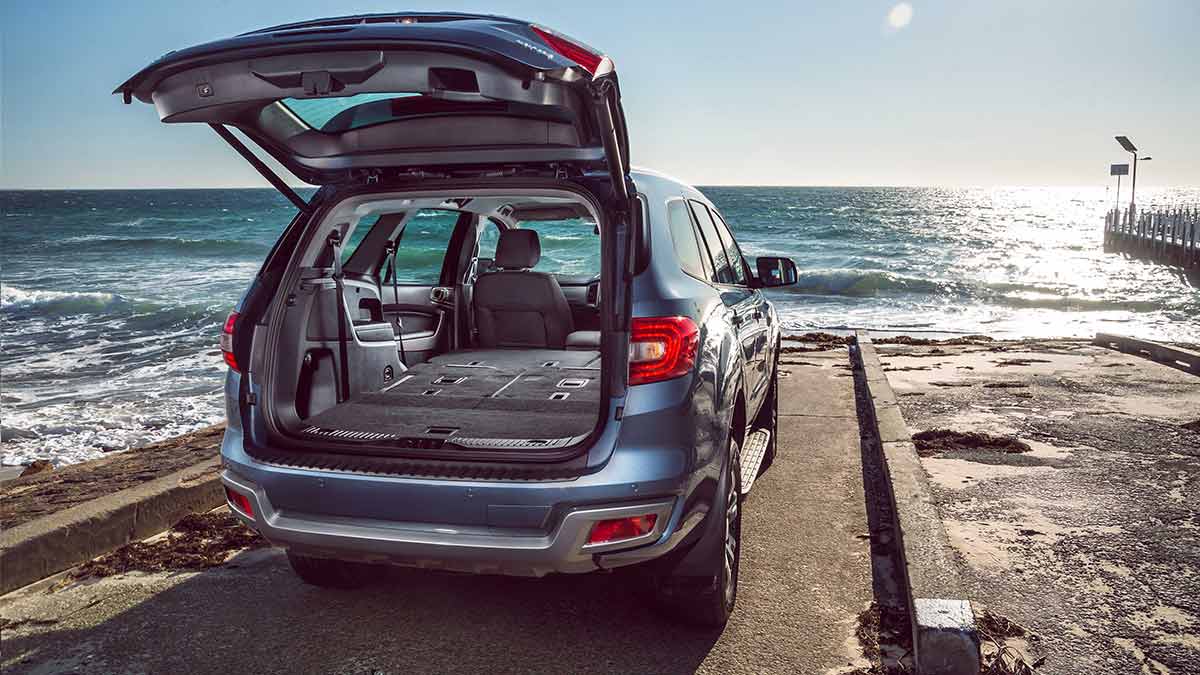 Rear view of a blue Ford Everest Trend parked near the water with the boot open